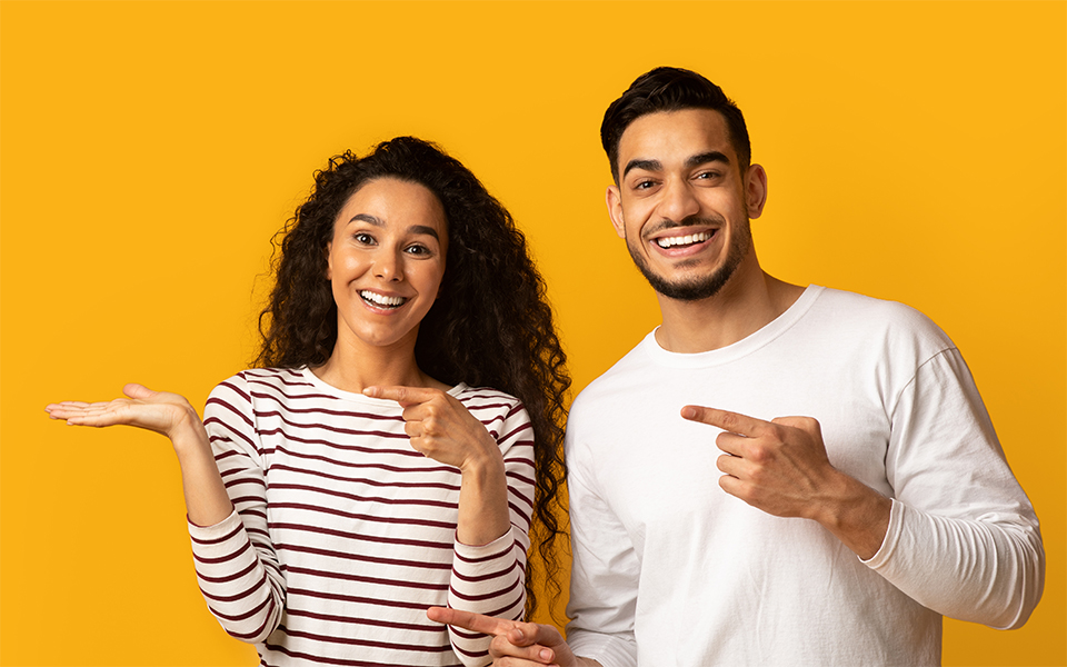 Junges Paar zeigt mit den Fingern in die linke Richtung